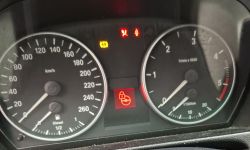 Zbliżenie na deskę rozdzielczą BMW E90 z zapalonymi kontrolkami ostrzegawczymi.