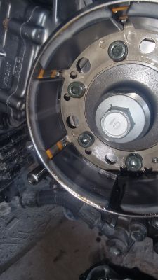 Zbliżenie na wewnętrzną część mechanizmu silnika ze śrubami i przekładnią.