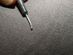 Test lead with thinly flattened end on a gray background.