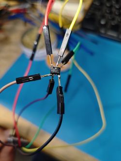 Close-up of a desoldered TSINGTENG Microsystem TH25Q-80UA chip with attached wires.