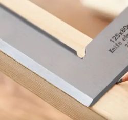 Close-up of a try square positioned on the corner of a wooden board