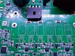 Zbliżenie na zieloną płytkę drukowaną z różnymi komponentami elektronicznymi.