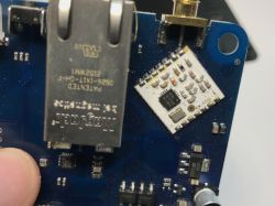 Close-up of a blue printed circuit board with an electronic module and an Ethernet port.