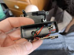 Casing with Electronics and Wires A person holding an open plastic casing with electronics and colorful wires inside.