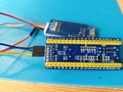STM32F103C8T6 Blue Pill Board Connected by Wires for Programming STM32F103C8T6 blue pill development board wired to another module on a blue electronics mat.
