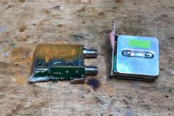 Dwa metalowe moduły elektroniczne na drewnianej powierzchni.