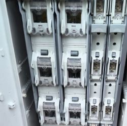 Zbliżenie na skrzynkę elektryczną z bezpiecznikami typu NH2 i szynami zasilającymi