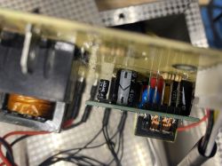 Widok wnętrza urządzenia elektronicznego z widocznymi kondensatorami i okablowaniem.