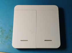 White double light switch with rounded edges on blue surface