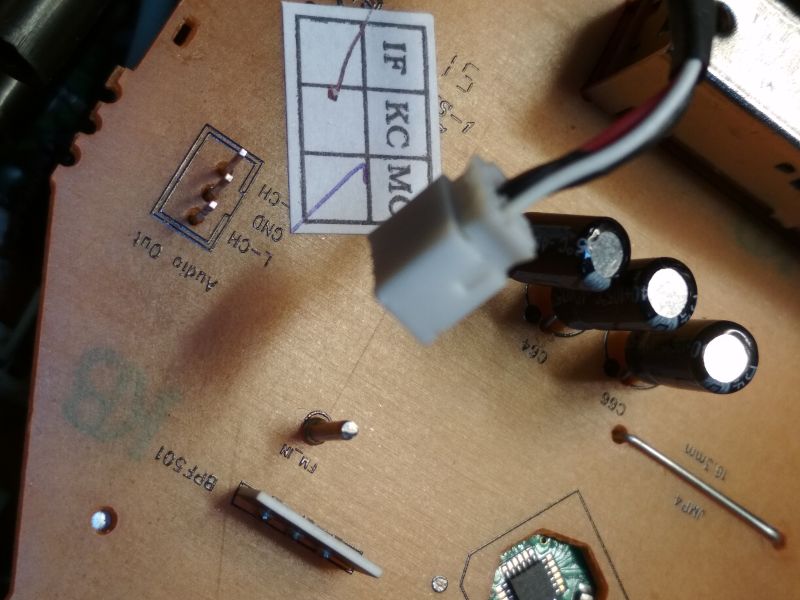 Zbliżenie na płytkę drukowaną z widoczną wtyczką, trzema kondensatorami elektrolitycznymi i opisami złączy.