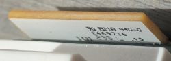 Close-up of a white electronic module with black printed text, with a white casing visible underneath.