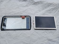 Dwa elementy wyświetlacza leżące na białym materiale – po lewej pęknięta szybka dotykowa, po prawej ekran LCD.