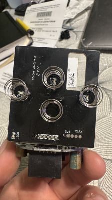 Electronic module with coils and connectors held in a hand.