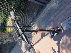 Hulajnoga elektryczna EO SCOOTER widziana od góry, stojąca przy ogrodzeniu.