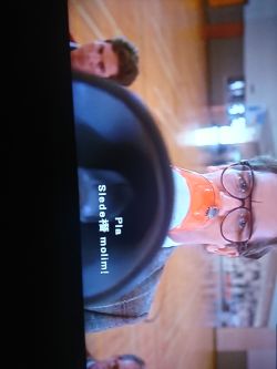 Man with glasses speaking through a megaphone in a gymnasium