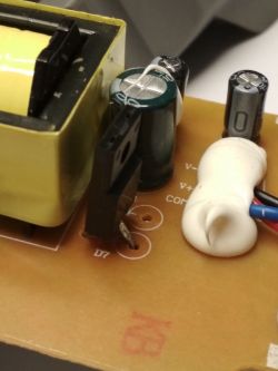 Zbliżenie na elementy elektroniczne na płytce drukowanej, w tym kondensatory i złącze.