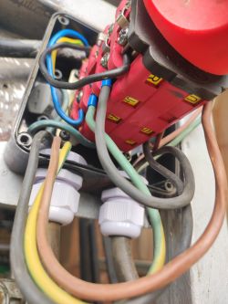 Widok wyłącznika elektrycznego z przewodami podłączonymi do zacisków, osadzony w metalowej obudowie.