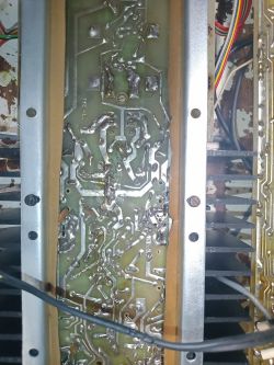 Widok na płytkę drukowaną z elementami elektronicznymi i ścieżkami przewodzącymi, otoczoną metalową ramą.