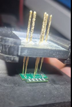Close-up of a prototype device with test pins connected to a PCB.