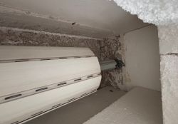 Mechanizm automatycznej rolety z widocznymi prowadnicami i obudową.