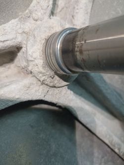 Zbliżenie na element mechaniczny z metalowym wałem i pokryciem pyłem lub osadem.