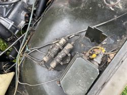 Przewody elektryczne i podzespoły pod maską pojazdu wojskowego, widoczny regulator napięcia.