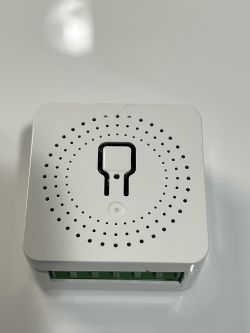 White Electronic Module with Perforation Pattern White, square electronic module with circular perforation pattern and green connector on one side.