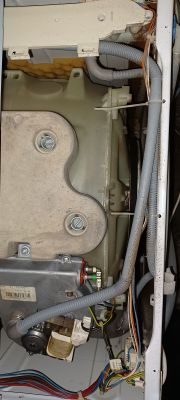 Wnętrze urządzenia z widoczną instalacją hydrauliczną i elektryczną.