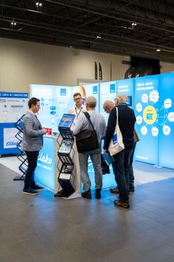 Eltabo trade show booth with glowing blue panels and several people talking at the counter.