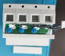 Close-up of the inside of a three-phase circuit breaker module showing a PCB with three blue capacitors.