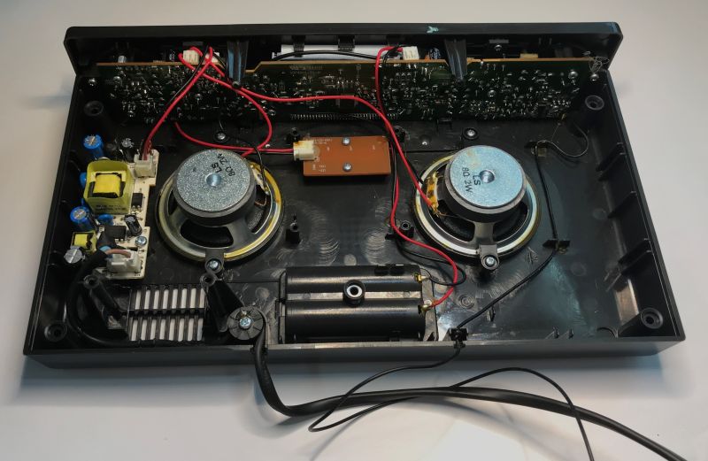 Inside an open clock radio: two speakers, PCB boards, wiring, and a power-supply module