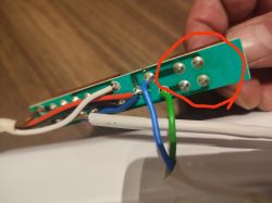 Zbliżenie na płytkę PCB z przylutowanymi przewodami i zaznaczonymi punktami lutowniczymi