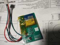 Electronic module with wires and antenna lying on a technical document.