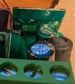 Damaged electrolytic capacitor on green PCB with visible bulging top