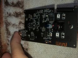 Black PCB with camera lens, LEDs and an antenna, held near a micro‑USB connector