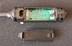 Otwarta obudowa elektronicznego urządzenia z widoczną płytką drukowaną i komorą na baterie AAA.