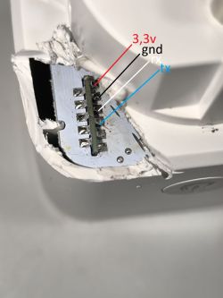 Close-up view of a damaged electronic device case with an exposed connector and labeled pins: 3.3V, GND, RX, TX.