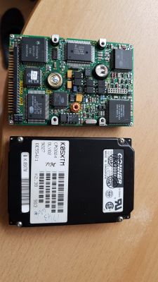 Old Conner hard drive and its circuit board lying on a wooden table.
