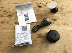 Wi-Fi mini camera with USB cable, mount, and manuals on wooden surface