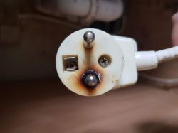Zbliżenie na nadtopioną wtyczkę z przedłużacza.