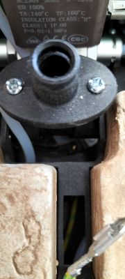 Zbliżenie na mechaniczny zawór elektromagnetyczny w ekspresie do kawy z widocznym otworem i przewodami.