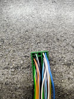 Zbliżenie na zieloną kostkę elektryczną z kolorowymi przewodami.