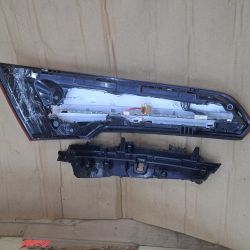 Disassembled rear car LED light showing circuit board and wiring on cardboard surface.