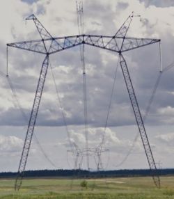 Słupy energetyczne na tle chmur na otwartej przestrzeni.