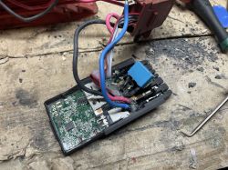 Otwarty moduł elektroniki z płytką PCB i przewodami na zabrudzonym blacie warsztatowym