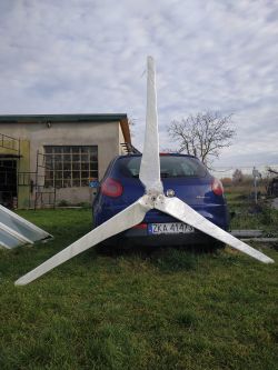 Trójłopatowe śmigło turbiny wiatrowej oparte o niebieski samochód Fiat Bravo
