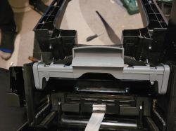 Inside a black plastic housing with a gray flap and side springs; a screwdriver lies in the background