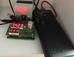 22.5W power bank connected to a USB meter with red LED displays, with cables and a metal heatsink behind