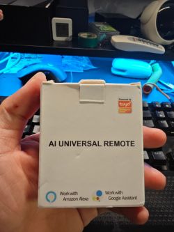 A person holding an AI Universal Remote box compatible with Amazon Alexa and Google Assistant.