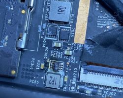 Zbliżenie na płytę główną laptopa z widocznymi elementami elektronicznymi i numerami oznaczeń.